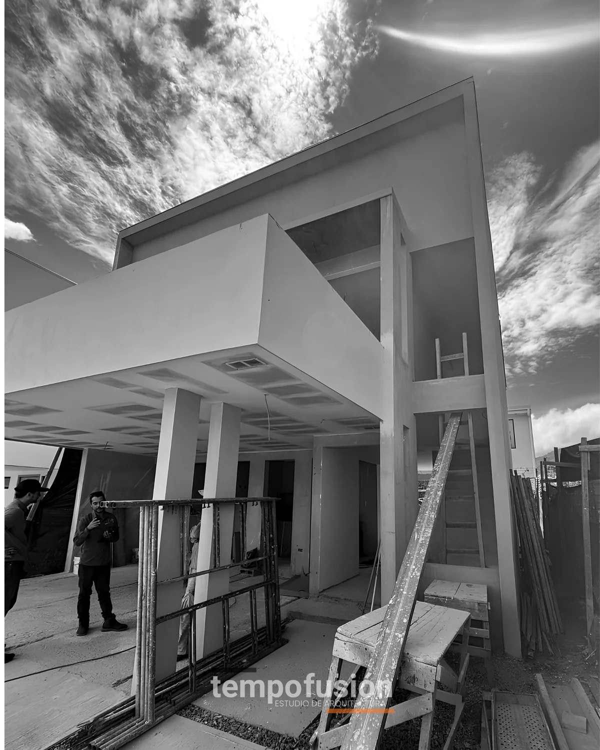 Obra en construcción con columnas de concreto y andamios, en blanco y negro